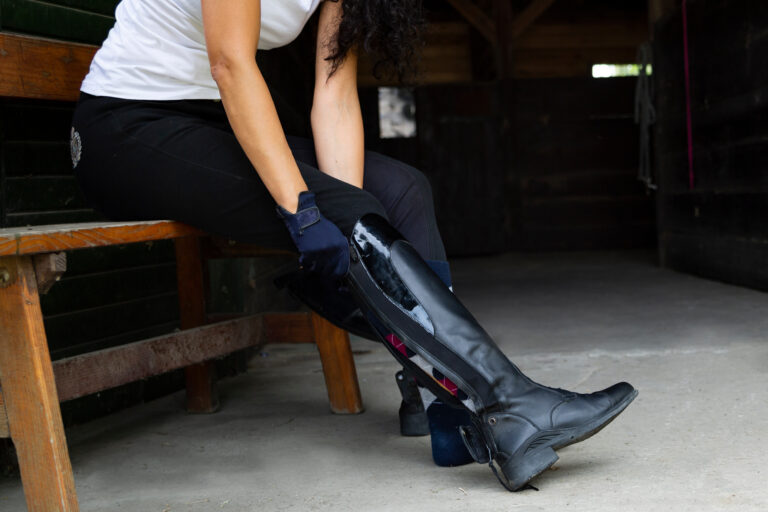 The Trainers Loft Horse Riding Boots, Stud, woman puts on professional leather riding boots.