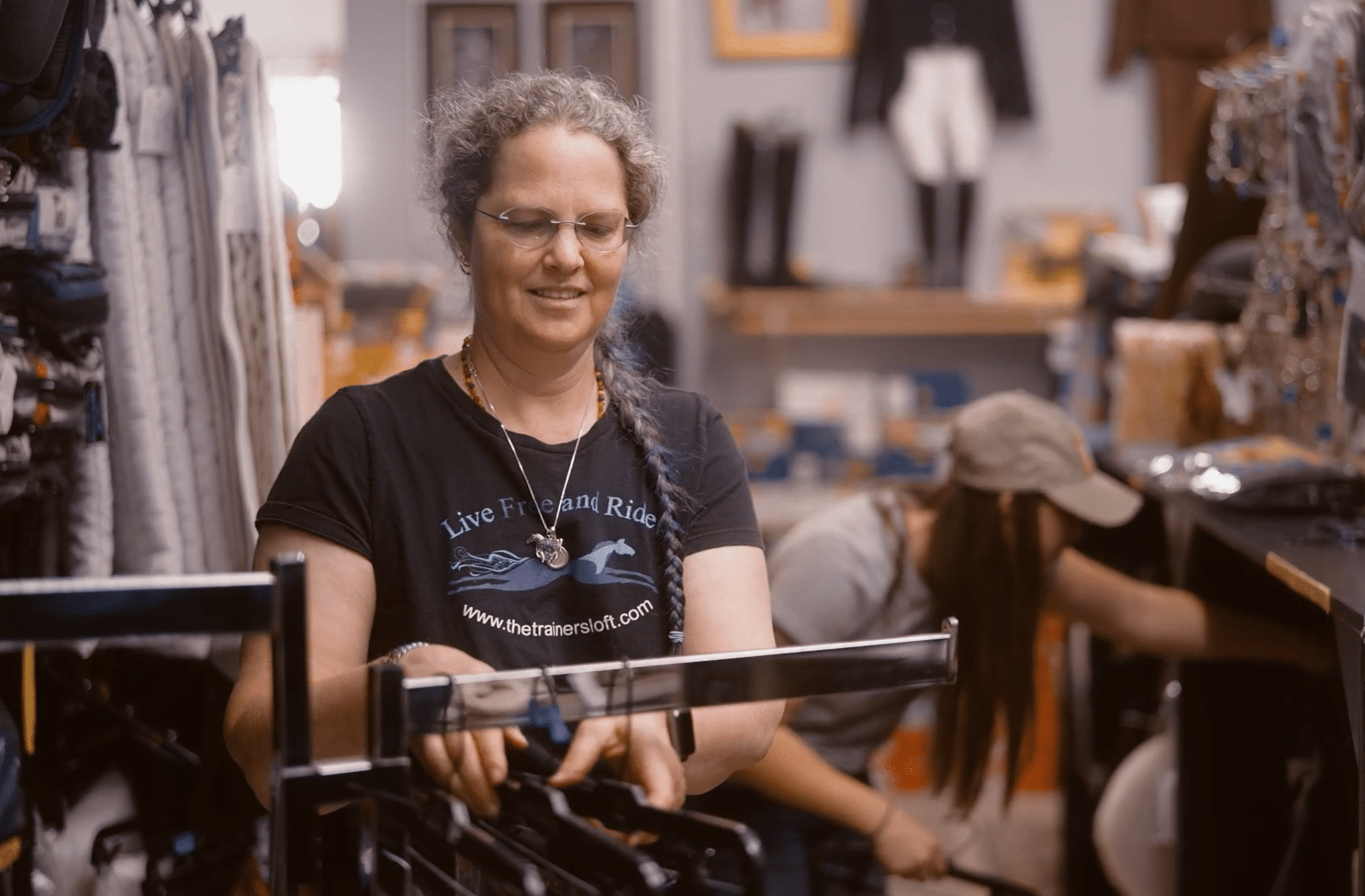 The Trainer's Loft equine tack shops near me, owner of the trainer's loft looks through clothing rack